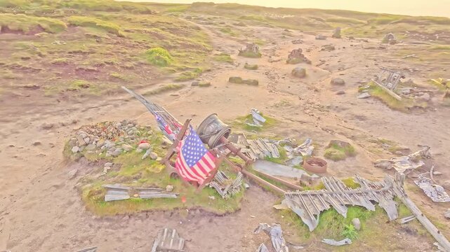 Aerial orbit over memorial stone grave at the B-29 Superfortress WWII plane crash site in the Peak District, England. American flag waving in the wind over historic site.
