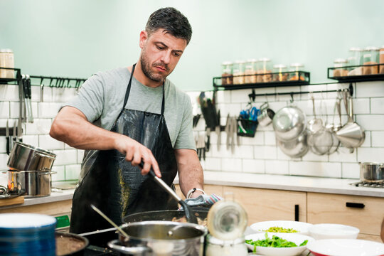 young man enjoying a group cooking class with a chef, learning to cook