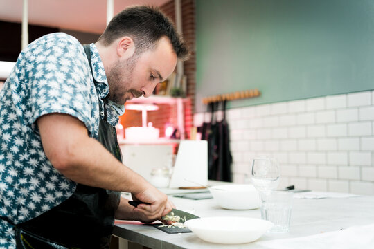 young man enjoying a group cooking class with a chef, learning to cook