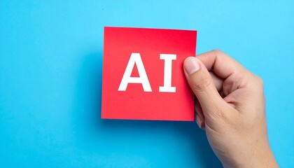 A hand holding a red sticky note with AI letters against a blue background. The image represents artificial intelligence, technology, and concepts