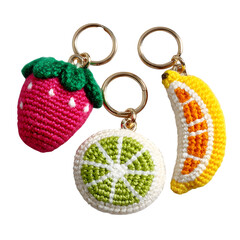 Bright crochet fruit keychains - strawberry, banana, and orange slice - vibrant yarn and fun food design, flat lay, isolated transparent background with minimal design