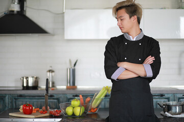 Asian cook in the kitchen prepares food in a cook suit