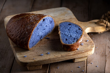 Freshly baked bread with a vibrant purple interior, cooked in blue Thai ancha tea, rests on a...
