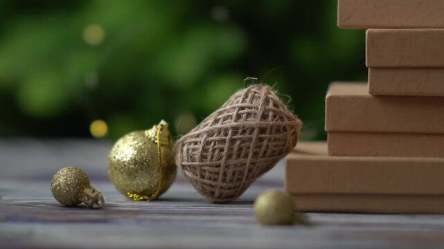 Holiday decor. Packing holiday gifts. Gift boxes and natural twine and Christmas gold balls on a Christmas tree background and bokeh. Moving focus across items