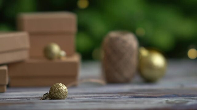 Holiday decor. Packing holiday gifts. Gift boxes and natural twine and Christmas gold balls on a Christmas tree background and bokeh. Moving focus across items
