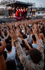 Festival crowd enjoying golden hour glow with hands raised during a lively performance at an outdoor venue