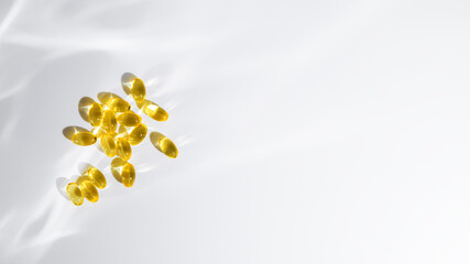 Yellow vitamin D or fish oil capsules on a white background, emphasizing themes of health, wellness, and nutrition, with copy space