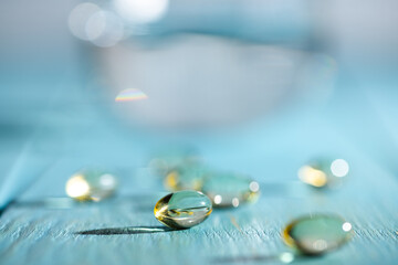 Softgels and fish oil, vitamin D capsules reflecting light against a blue background, creating a...
