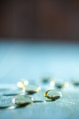 Softgels and fish oil, vitamin D capsules reflecting light against a blue background, creating a stunning bokeh effect while highlighting the importance of health and wellness in daily nutrition