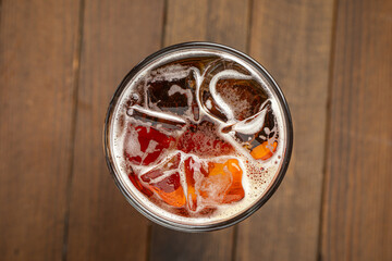 Glass of cold kvass with ice cubes on wooden table