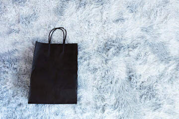 Black paper bag on wool sheep background, Shopping paper bag, Synthetic sheep fur 