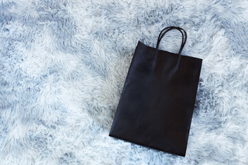 Black paper bag on wool sheep background, Shopping paper bag, Synthetic sheep fur 