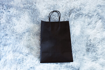 Black paper bag on wool sheep background, Shopping paper bag, Synthetic sheep fur 