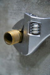 Close-up of a plumber using an adjustable wrench to tighten a brass pipe fitting, ensuring a secure...