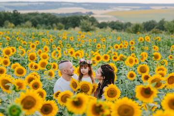 Happy family in a field of sunflowers in summer