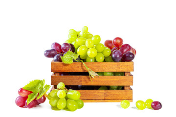 Bunches of green and red juicy grapes with leaves in a wooden box.