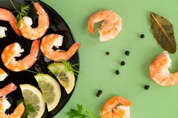 Boiled seafood shrimps with lemon isolated on green background