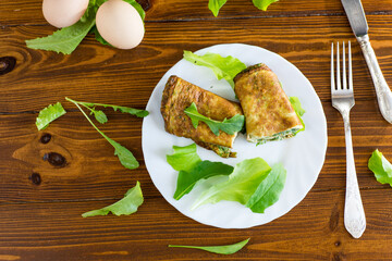 Omelette roll with greens and fresh arugula on a plate