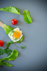 Close-up of tasty egg with salad leaves in kitchen, on gray background