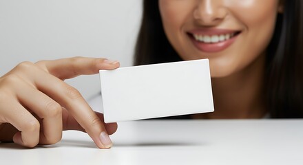 Close-up of a woman holding a blank business card, smiling warmly. Mockup