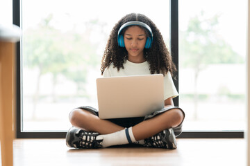 African American male student or kid studying online by using laptop computer and wearing headphone...