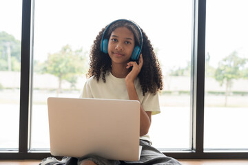 African American male student or kid studying online by using laptop computer and wearing headphone...