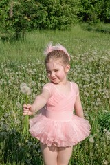 Adorable Ballerina Girl  in a pink tutu with Dandelions in a Grassy Meadow. Springtime Delight.