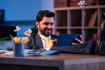 Feet on desk, Indian professional uses tablet, representing relaxed modern business lifestyle