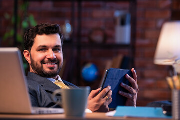 Feet on desk, Indian professional uses tablet, representing relaxed modern business lifestyle