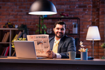 Executive reads business paper at desk, showing focus, awareness, and interest in financial updates