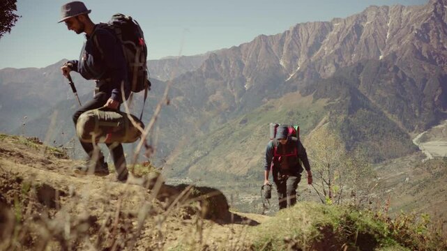 A man with a camping backpack walks toward the mountaintop, trekking through the wilderness near Bhrigu Lake, Manali, Himachal Pradesh, India. - Powered by Adobe
