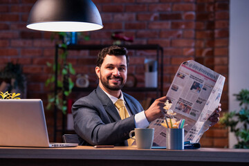 Executive reads business paper at desk, showing focus, awareness, and interest in financial updates