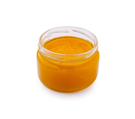 Bright golden honey jar in a clear glass container on a white background