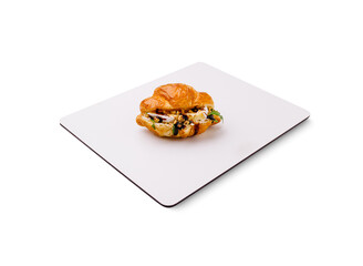 Gourmet croissant filled with savory ingredients on a clean surface