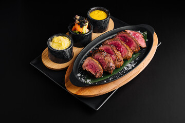 Perfectly cooked steak served with sides on a black table