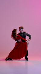 Argentine tango dancers hold a striking pose beneath pink and purple stage lights, exuding grace...