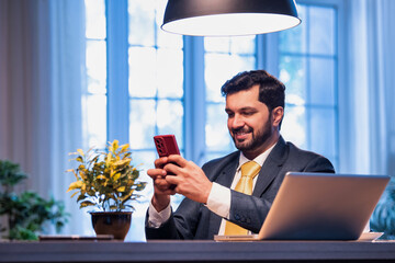Corporate man typing on phone at work desk, representing modern business communication and focus