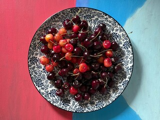 Fresh cherries in decorative bowl on colorful background showcasing vibrant fruit arrangement
