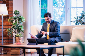 Indian executive joins virtual meeting with tablet and documents, showing focus and multitasking