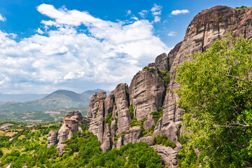 Ancient Meteora monastery perched on cliff edge beside massive rock formation in Greece