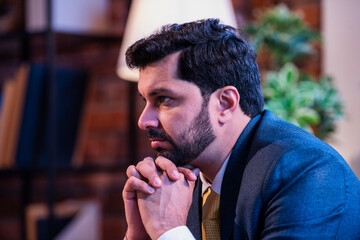 Indian businessman thinking seriously while seated on office couch, symbolizing focus and planning