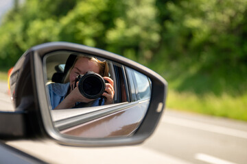 Photographer taking picture reflected in car side mirror on sunny day