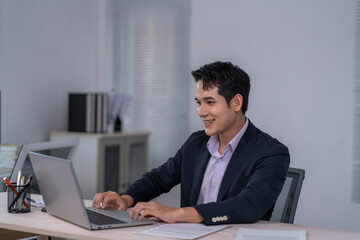 A man in a suit is sitting at a desk with a laptop in front of him
