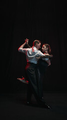 A pair passionately dances an Argentine tango under a dramatic spotlight. Concept of deep emotion and cultural expression in movement.
