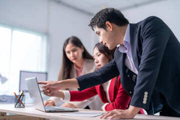 A man points to a laptop screen while two women look on