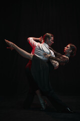 Dancers execute a passionate, elegant Argentine tango pose against a striking dark backdrop. Concept of cultural expression and grace in movement.