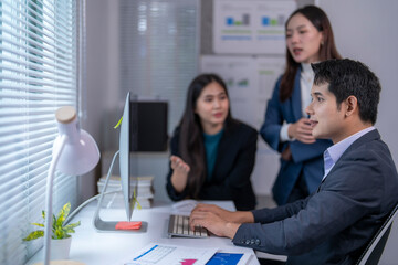 Three people are in a meeting room, with a man in a suit