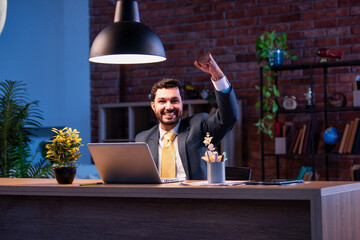 Indian businessman celebrates success at work with laptop, expressing victory and happiness
