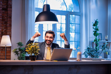 Indian businessman celebrates success at work with laptop, expressing victory and happiness