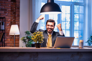 Indian businessman celebrates success at work with laptop, expressing victory and happiness